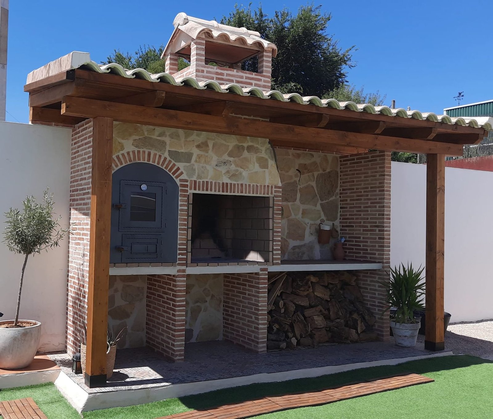 Porche de obra con pérgola de madera y barbacoa de piedra